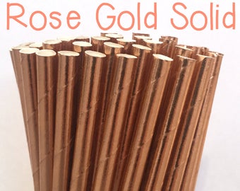 May include: A bunch of rose gold paper straws in a glass jar. The straws are striped and have a metallic finish.