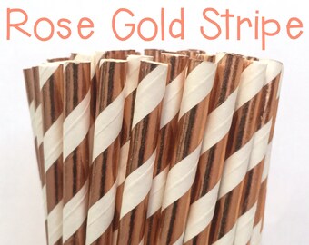 May include: A close-up of a bunch of rose gold and white striped paper straws in a glass jar. The straws are perfect for adding a touch of elegance to any party or event.