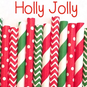 May include: A collection of red and green striped, polka dot, and chevron patterned paper straws. The straws are arranged in a row and the text "Holly Jolly" is written above them.