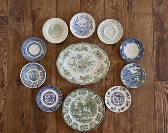 May include: A collection of ten ceramic plates and saucers arranged in a circular pattern. The set includes various pieces with blue and white or green and white transferware patterns, featuring floral motifs, landscape scenes, and decorative borders.