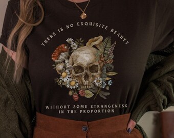 May include: A black t-shirt with a skull and floral design. The text on the shirt reads "There is no exquisite beauty without some strangeness in the proportion."