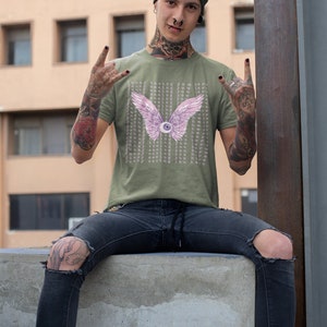 May include: A green t-shirt with a pink eye with wings graphic and the text "Funny seeing you here" repeated multiple times. The person wearing the shirt has green hair and tattoos.