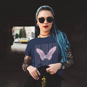 May include: A navy blue t-shirt with a pink and white eye with wings graphic. The text "Funny seeing you here" is repeated in a pattern on the shirt.