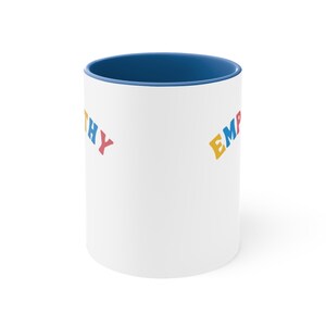May include: White ceramic mug with a blue rim. The mug has the words "Empathy" and "Empathy" printed on it in colorful letters.