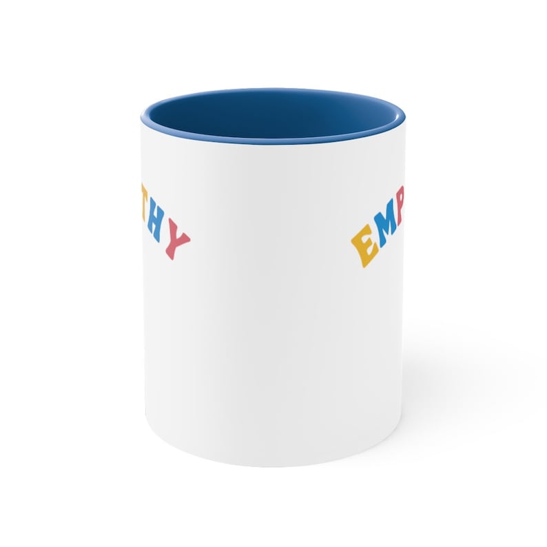 May include: White ceramic mug with a blue rim. The mug has the words "Empathy" and "Empathy" printed on it in colorful letters.