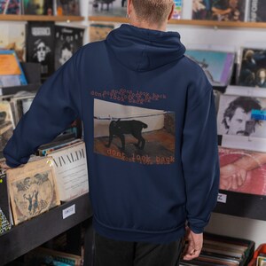May include: A navy blue hoodie with a black cat graphic and the text "dont look back dont look back dont look back dont look back" on the back.