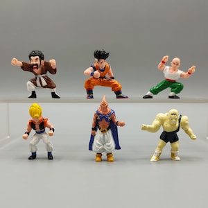 May include: Six small, colorful figurines of characters from the Dragon Ball Z anime series. The figures are in various action poses and feature detailed designs. The characters are wearing outfits in shades of orange, green, white, and blue.