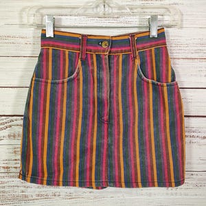 May include: A colorful striped denim mini skirt with a high waist and pockets. The skirt has vertical stripes in shades of pink, orange, yellow, blue, and green.