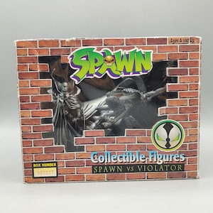 May include: A collectible figure box featuring the Spawn vs. Violator characters. The box has a brick wall design with the Spawn logo in green and purple. The box also includes the text "Collectible Figures" and "Ages 4 and Up".