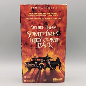 May include: A VHS tape for Stephen King's "Sometimes They Come Back" featuring Tim Matheson. The cover has a fiery background with a black car and figures. The title is in a stylized font.