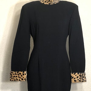 May include: A black dress with a mock neck and long sleeves. The collar and cuffs are trimmed with a brown and black leopard print fabric.