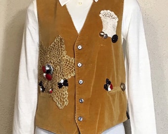 May include: A brown velvet vest with a crocheted star design on the left side and a crocheted flower design on the right side. The vest has five buttons down the front.