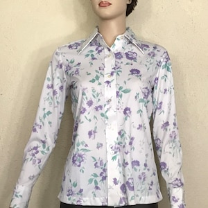 May include: A white long-sleeved button-up shirt with a floral pattern in shades of purple and green.