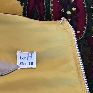 May include: A yellow fabric tag with the text "Lot 14" and "Size 10" printed on it.