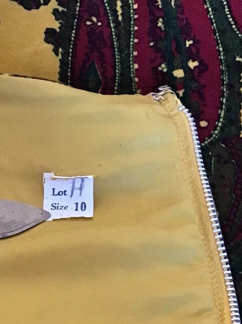 May include: A yellow fabric tag with the text "Lot 14" and "Size 10" printed on it.