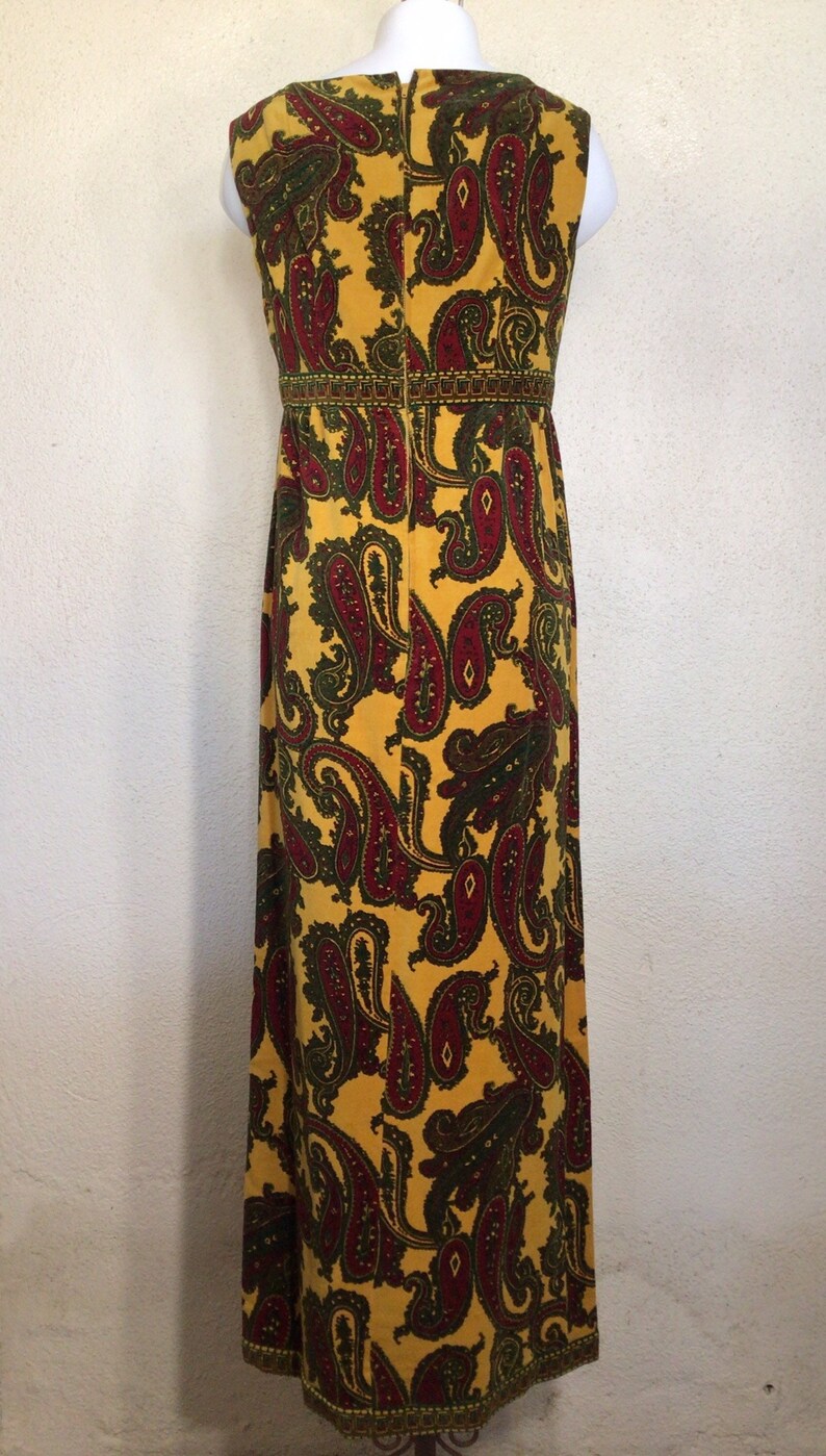 May include: A long yellow maxi dress with a paisley pattern in shades of red and green. The dress has a sleeveless design and a fitted bodice.