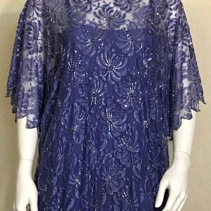 May include: A purple sequined lace dress with a high neck and short sleeves. The dress has a floral pattern and is made of a sheer fabric.