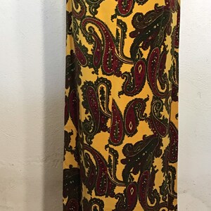 May include: A long yellow skirt with a paisley pattern in shades of burgundy and green. The skirt has a gold trim around the bottom.