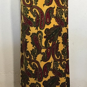 May include: A long yellow maxi skirt with a paisley pattern in shades of green and burgundy. The skirt has a gold trim around the bottom.