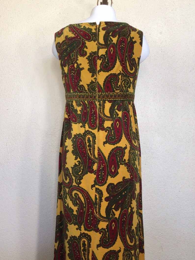 May include: A long yellow maxi dress with a paisley pattern in shades of red and green. The dress has a sleeveless design and a back zip closure.