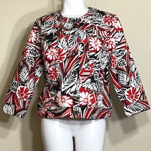May include: A red, white, and black floral print jacket with a button closure. The jacket has a fitted silhouette and three-quarter sleeves.