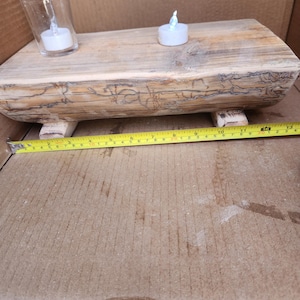 May include: A rustic wooden log candle holder with two tealight candles. The log is approximately 15 inches long and has a natural wood finish.