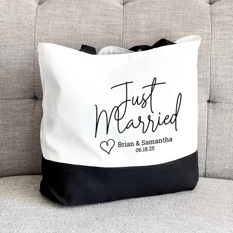 A Just Married Tote Bag. Wedding Tote bag is canvas white with a black base and handles. Customized with your names and wedding date on the bottom under the words just married and next to a cute heart. A great wedding gift.