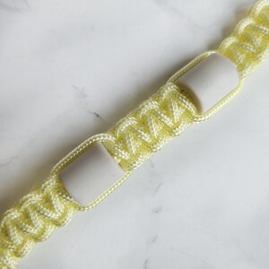 Op de afbeelding: Geel paracord anti-teken bandje. Kleur optie : Lightning