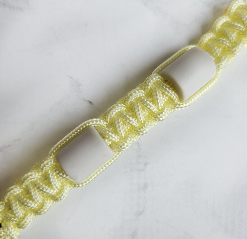 Op de afbeelding: Geel paracord anti-teken bandje. Kleur optie : Lightning