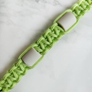 Op de afbeelding: Groen paracord anti-teken bandje. Kleur optie : Ufo