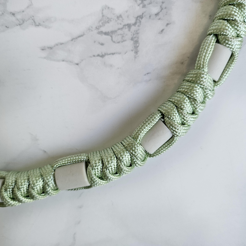 Op de afbeelding: Groen paracord anti-teken bandje. Kleur optie : Ufo