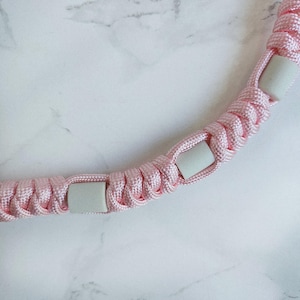 Op de afbeelding: Roze paracord anti-teken bandje. Kleur optie : Fata morgana