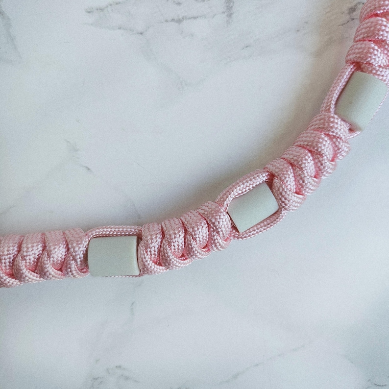 Op de afbeelding: Roze paracord anti-teken bandje. Kleur optie : Fata morgana