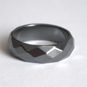 Peut inclure: Une bague en hématite noire facetée. La bague est faite d'une pierre lisse et polie et présente un design géométrique.