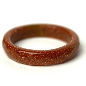 May include: A brown ring made of sunstone with a sparkly finish.