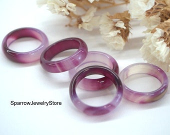 May include: Six purple and white marbled rings are arranged on a white surface. The rings vary in shades of purple, from deep violet to pale lavender. The rings are made of a translucent material. The text "SparrowJewelryStore" is visible.