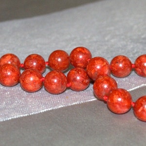 Peut inclure: Un collier de corail rouge avec un fermoir en argent. Le collier est compos&eacute; de perles rondes et est enfil&eacute; sur un cordon rouge.