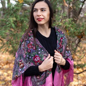 May include: A pink shawl with a floral pattern and fringe. The shawl is made of silk and has a traditional Russian design. The shawl is worn by a person in a forest setting.