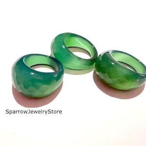 May include: Three green gemstone rings with faceted surfaces are displayed on a white background. The rings have a chunky, rounded design. The text "SparrowJewelryStore" is visible at the bottom left of the image.