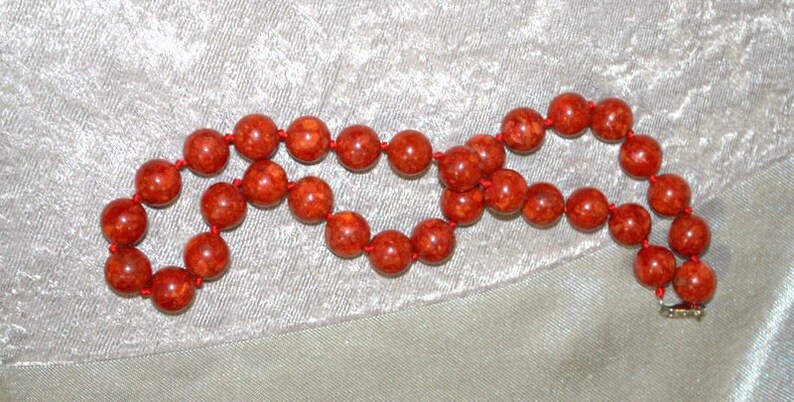 Peut inclure: Un collier de perles de corail rouge avec une fermeture &agrave; fermoir. Les perles sont rondes et ont une surface naturelle et textur&eacute;e.