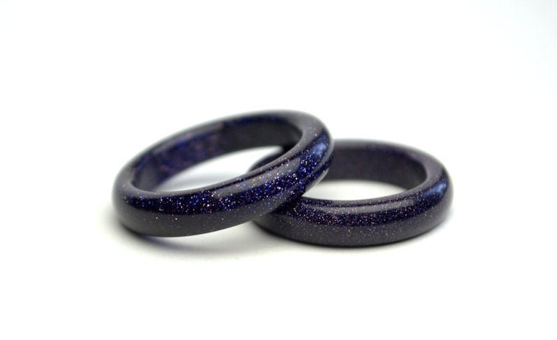 May include: Two dark blue rings made of blue sandstone. The rings are smooth and have a speckled texture.