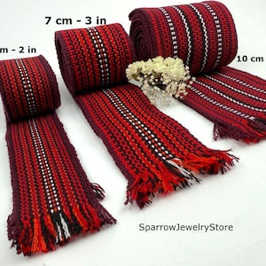 Könnte beinhalten: Nahaufnahme von mehreren gewebten rot-schwarzen Stoffstreifen mit weißen Akzentstreifen. Die Streifen sind 5, 7 und 10 cm breit und haben Fransen an den Enden. Das Bild enthält den Text "SparrowJewelryStore".