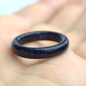 May include: A dark blue ring made of blue sand stone. The ring is smooth and polished.