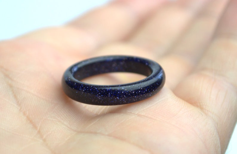 May include: A dark blue ring made of blue sand stone. The ring is smooth and polished.