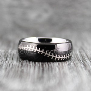 May include: A black tungsten carbide ring with a white baseball stitch design.