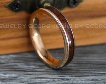Puede incluir: Un anillo de madera de color dorado y marrón con un acabado pulido. El anillo está sobre una superficie de madera.