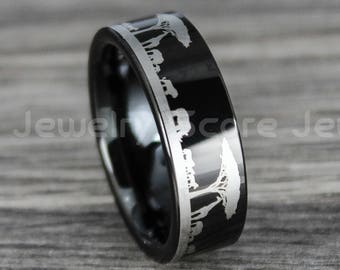 May include: Black ring with a silver engraved design of giraffes and trees. The ring has a polished finish and a band width of approximately 8mm. The ring is a piece of jewelry.