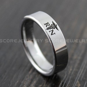 May include: A silver ring with a black engraved medical symbol and the letters "RN".