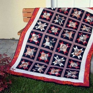 May include: A quilt with a red, white, and blue color scheme featuring a repeating pattern of stars and cats. The quilt is made of fabric squares sewn together.