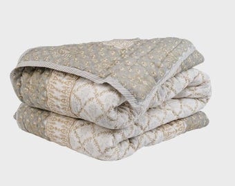 May include: A folded gray and white patterned quilt with a floral design. The quilt is made of cotton and has a soft, comfortable feel.